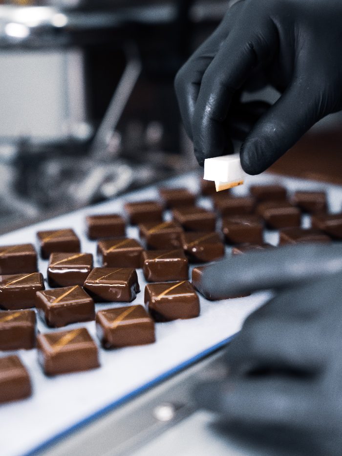 Pose du décor doré à la main sur les chocolats, atelier Geoffrey Gil